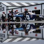 
              Crew members are reflected in a puddle as they push the car of Landon Cassill through the garage area during inspections for Saturday's NASCAR Xfinity Series auto race at Pocono Raceway, Friday, July 22, 2022, in Long Pond, Pa. (AP Photo/Matt Slocum)
            