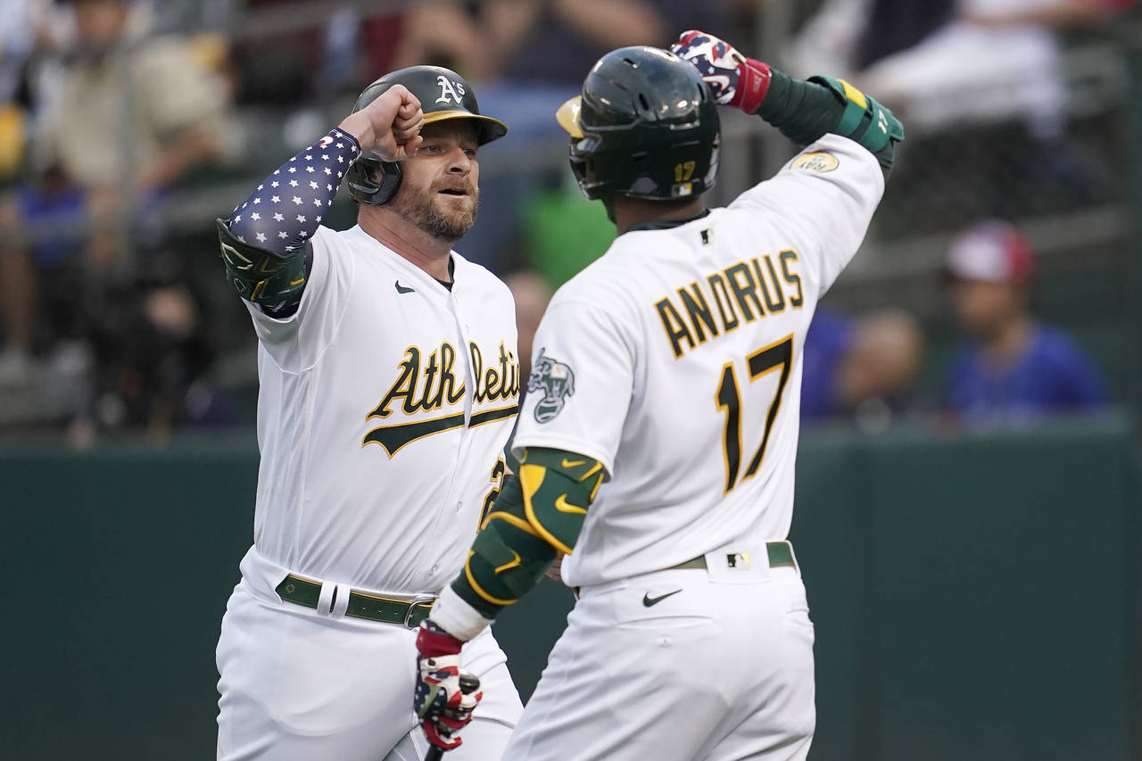 Oakland Athletics' Stephen Vogt, left, is congratulated by Elvis Andrus after hitting a home run ag...