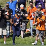 
              Denver Broncos quarterback Russell Wilson heads back to the practice field after greeting fans along a rope line before the opening session of the NFL football team's training camp Wednesday, July 27, 2022, in Centennial, Colo. (AP Photo/David Zalubowski)
            