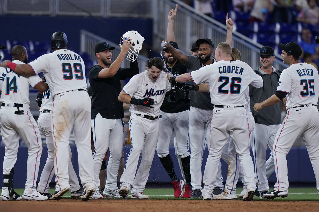 Teammates mob Miami Marlins' Brian Anderson, center, after Anderson tripled scoring Jesus Aguilar a...