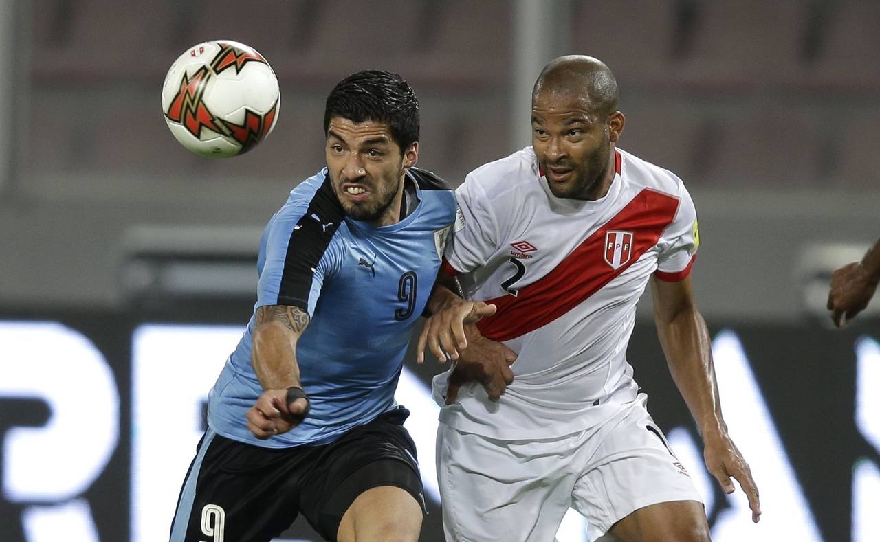 El delantero uruguayo Luis Suárez (izquierda) pugna un balón con el peruano Alberto Rodríguez du...