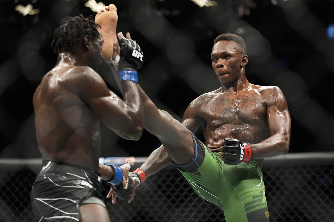 Israel Adesanya, right, kicks Jared Cannonier in a middleweight title bout during the UFC 276 mixed...