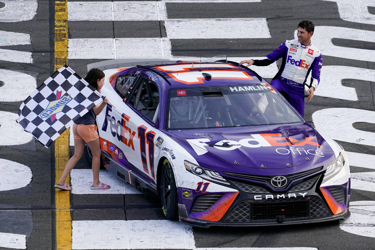 ADDS THAT HAMLIN WAS LATER DISQUALIFIED - Taylor James Hamlin, left, carries the checkered flag wit...