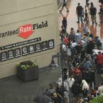 
              Lines of fans wait to go through added security while a bomb-sniffing dog and its handler look on at Guaranteed Rate Field after a Fourth of July parade shooting in nearby Highland Park, Ill., Monday, July 4, 2022, in Chicago before a baseball game between the Chicago White Sox and the Minnesota Twins. (AP Photo/Paul Beaty)
            