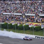 
              Denny Hamlin (11) does a burnout in front of the grand stand as he celebrates after winning the NASCAR Cup Series auto race at Pocono Raceway, Sunday, July 24, 2022, in Long Pond, Pa. (AP Photo/Matt Slocum)
            