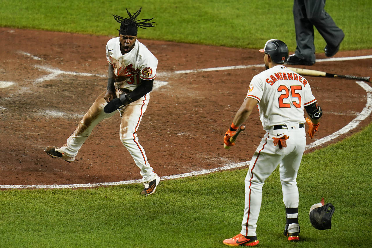 Baltimore Orioles' Cedric Mullins, left, reacts after scoring from second base on a two-run bases l...