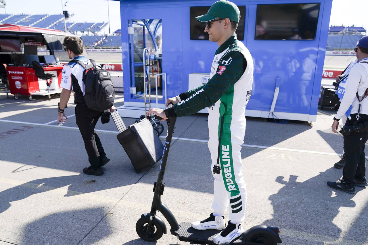 Alex Palou, of Spain, rides a scooter to the garage area following a practice for an IndyCar Series...