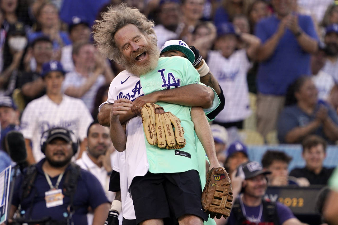 Actor Bryan Cranston is lifted by former Los Angeles Dodgers player Andre Ethier during the MLB All...