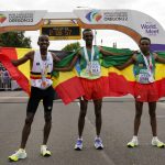 
              Gold medalist Tamirat Tola, of Ethiopia, center, stands with silver medalist Mosinet Geremew, of Ethiopia, right, and bronze medalist Bashir Abdi, of Belgium, after the men's marathon at the World Athletics Championships on Sunday, July 17, 2022, in Eugene, Ore. (AP Photo/Gregory Bull)
            