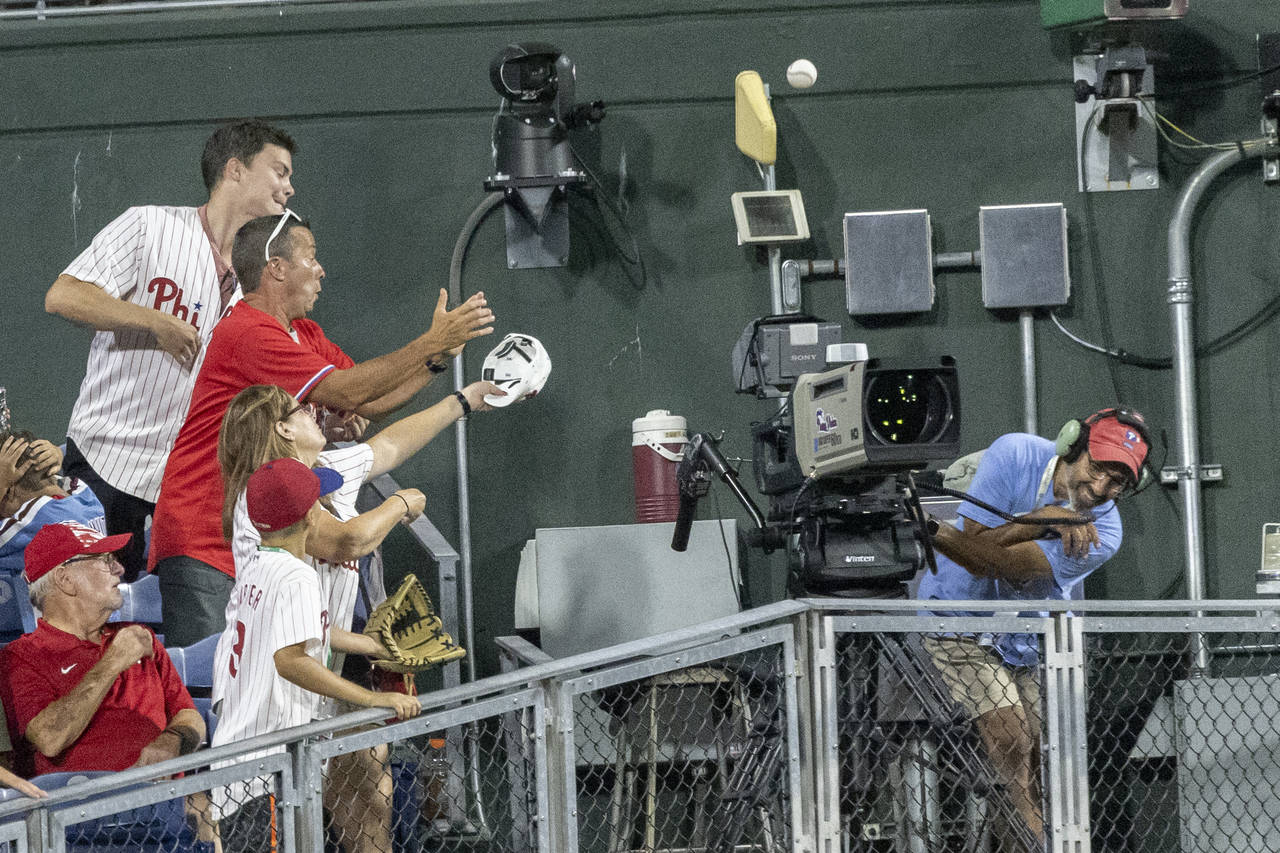 Fans reach for the ball as a television cameraman ducks, on a two-run home run by Chicago Cubs' Nel...
