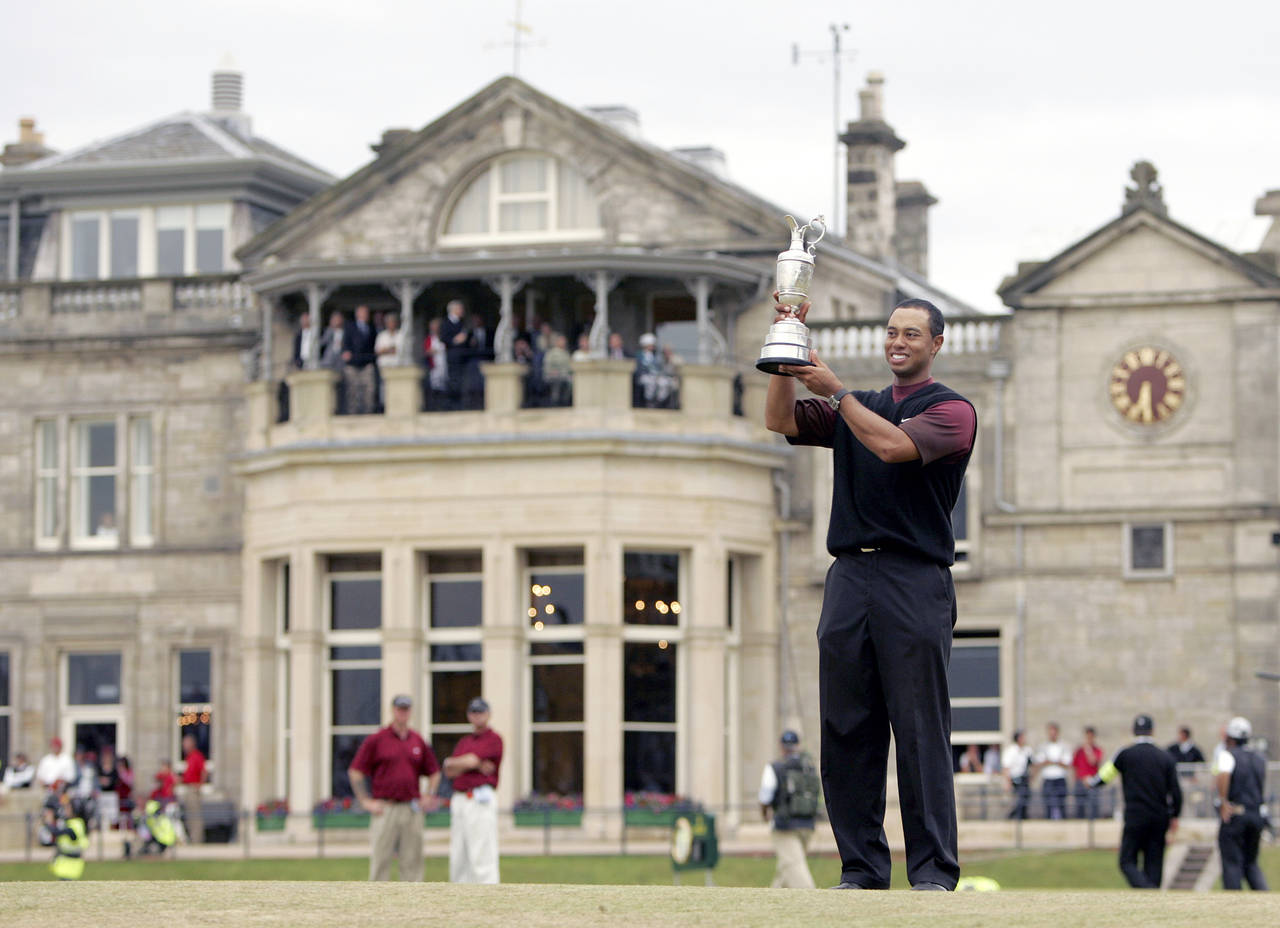 FILE - Tiger Woods holds the trophy as he stands in front of the clubhouse after winning the Britis...