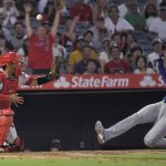 
              Texas Rangers' Marcus Semien, right, scores after hitting a double and then advancing to home on a fielding error by left fielder Jo Adell as Los Angeles Angels catcher Kurt Suzuki fumbles the ball during the sixth inning of a baseball game Friday, July 29, 2022, in Anaheim, Calif. (AP Photo/Mark J. Terrill)
            