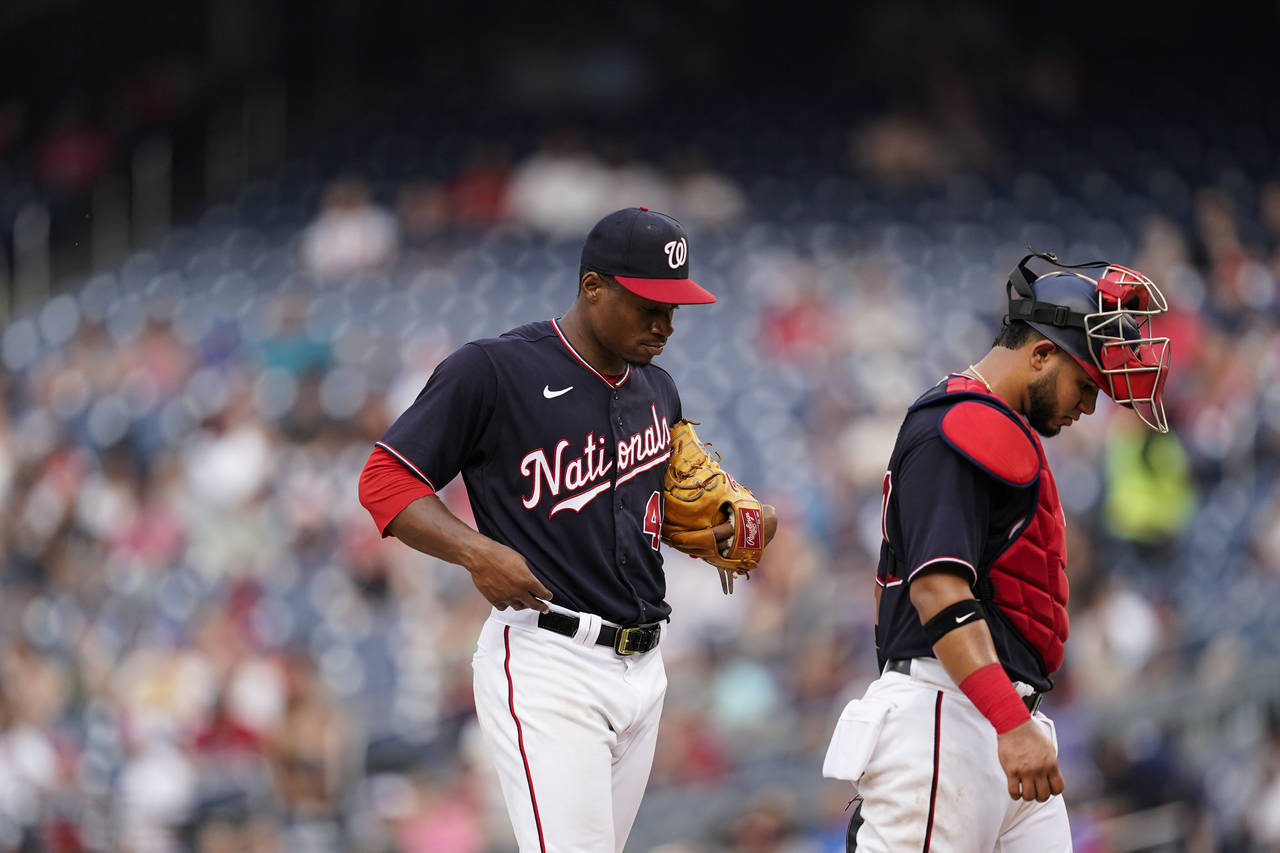 Washington Nationals starting pitcher Josiah Gray, left, stands on the mound after talking with cat...
