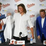 
              CORRECTS DATE -  Jackson Holliday, center, the first overall draft pick by the Baltimore Orioles in the 2022 draft, gets a jersey from general manager Mike Elias, left, as agent Scot Boras looks on during a news conference introducing him to the Baltimore media prior to a baseball game between the Baltimore Orioles and the Tampa Bay Rays, Wednesday, July 27, 2022, in Baltimore. (AP Photo/Julio Cortez)
            