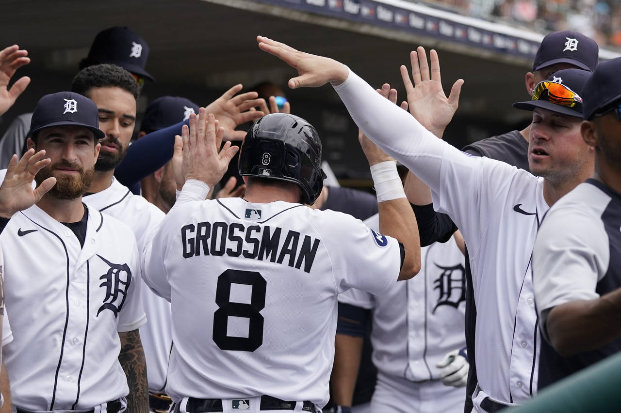 Detroit Tigers' Robbie Grossman is greeted in the dugout after scoring on a sacrifice hit by Miguel...