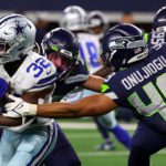 ARLINGTON, TEXAS - AUGUST 26: Aaron Shampklin #32 of the Dallas Cowboys runs as Joshua Onujiogu #49 of the Seattle Seahawks tries to tackle him in the second quarter in an NFL preseason football game at AT&T Stadium on August 26, 2022 in Arlington, Texas. (Photo by Richard Rodriguez/Getty Images)
