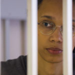 
              WNBA star and two-time Olympic gold medalist Brittney Griner looks through bars as she listens to the verdict standing in a cage in a courtroom in Khimki just outside Moscow, Russia, Thursday, Aug. 4, 2022. A judge in Russia has convicted American basketball star Brittney Griner of drug possession and smuggling and sentenced her to nine years in prison. (Evgenia Novozhenina/Pool Photo via AP)
            