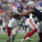 
              New York Giants running back Saquon Barkley (26) runs with the ball as New England Patriots defensive tackle Carl Davis Jr. (98) defends during the first half of a preseason NFL football game Thursday, Aug. 11, 2022, in Foxborough, Mass. (AP Photo/Charles Krupa)
            