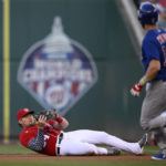 
              Washington Nationals first baseman Luke Voit, left, falls to the ground after he caught a popup by Chicago Cubs' Patrick Wisdom (16) during the first inning of a baseball game Tuesday, Aug. 16, 2022, in Washington. (AP Photo/Nick Wass)
            