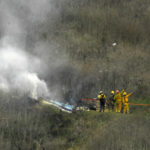 
              FILE - Firefighters work the scene of a helicopter crash where former NBA basketball star Kobe Bryant died in Calabasas, Calif., Jan. 26, 2020. Bryant's widow is taking her lawsuit against the Los Angeles County Sheriff's Department and Fire Department to a federal jury seeking compensation for photos deputies shared of the remains of the NBA star, his daughter and seven others killed in a helicopter crash in 2020. (AP Photo/Mark J. Terrill, File)
            