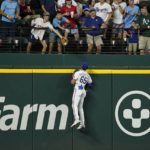 
              Texas Rangers left fielder Bubba Thompson leaps to the top of the wall to see a fan attempting to catch a two-run home run hit by Oakland Athletics' Elvis Andrus during the seventh inning of a baseball game in Arlington, Texas, Tuesday, Aug. 16, 2022. (AP Photo/Tony Gutierrez)
            