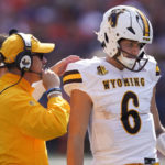 
              Wyoming running backs coach Gordie Haug, left, talks with quarterback Andrew Peasley during the first half of an NCAA college football game against Illinois Saturday, Aug. 27, 2022, in Champaign, Ill. (AP Photo/Charles Rex Arbogast)
            