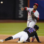 
              Philadelphia Phillies' Jean Segura, top, throws out New York Mets' Darin Ruf at first base after forcing out Francisco Lindor (12) for a double play during the fourth inning of a baseball game Friday, Aug. 12, 2022, in New York. (AP Photo/Frank Franklin II)
            