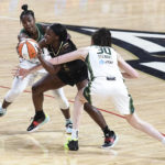 
              Las Vegas Aces guard Jackie Young, center, cuts between Seattle Storm guard Jewell Loyd, left, and forward Breanna Stewart (30) during the first half of a WNBA basketball game Sunday, Aug. 14, 2022, in Las Vegas. (AP Photo/Sam Morris)
            