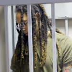 
              WNBA star and two-time Olympic gold medalist Brittney Griner stands behind bars in  a courtroom prior to a hearing in Khimki just outside Moscow, Russia, Tuesday, Aug. 2, 2022. Since Brittney Griner last appeared in her trial for cannabis possession, the question of her fate expanded from a tiny and cramped courtroom on Moscow's outskirts to the highest level of Russia-US diplomacy. (Evgenia Novozhenina/Pool Photo via AP)
            