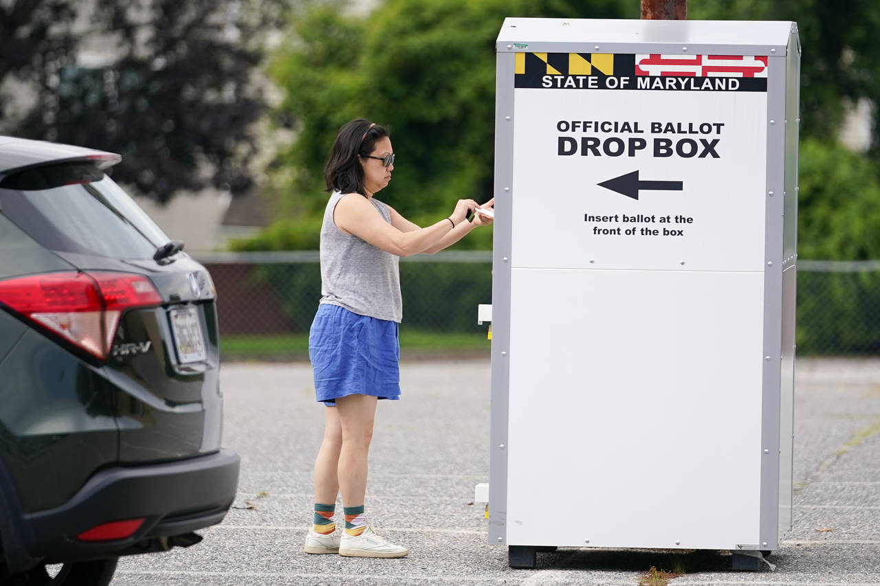FILE - A woman drops a ballot into a drop box while casting her vote during Maryland's primary elec...