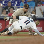 
              Miami Marlins' Miguel Rojas (11) slides safely into third base on a triple as San Diego Padres third baseman Manny Machado (13) is late with the tag in the sixth inning of a baseball game, Monday, Aug. 15, 2022, in Miami. (AP Photo/Marta Lavandier)
            