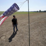 
              FILE — Hay farmer Milan Adams stands in a dry hay field near a wind sock, in Exeter, R.I., Tuesday, Aug. 9, 2022. Adams said in prior years it rained in the spring. This year, he said, the dryness started in March, and April was so dry he was nervous about his first cut of hay. Arid conditions in the northeastern U.S. have benefited amusement parks, minor league baseball teams, construction contractors and other businesses that need warm, dry weather to attract paying customers and get jobs completed on time. (AP Photo/Steven Senne, File)
            