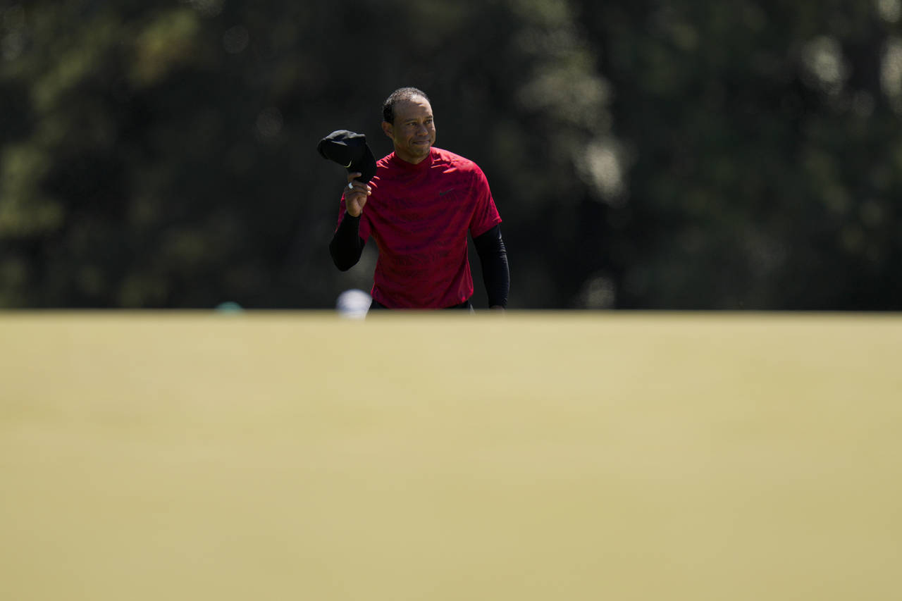 FILE - Tiger Woods tips his cap as he walks to the 18th green during the final round at the Masters...