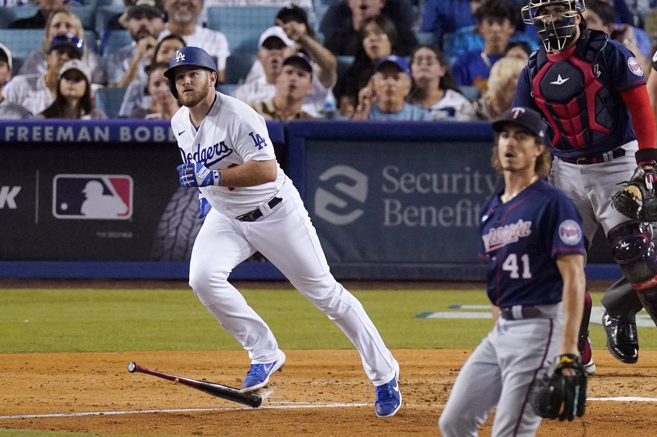 Los Angeles Dodgers' Max Muncy, left, heads to first as he hits a solo home run while Minnesota Twi...