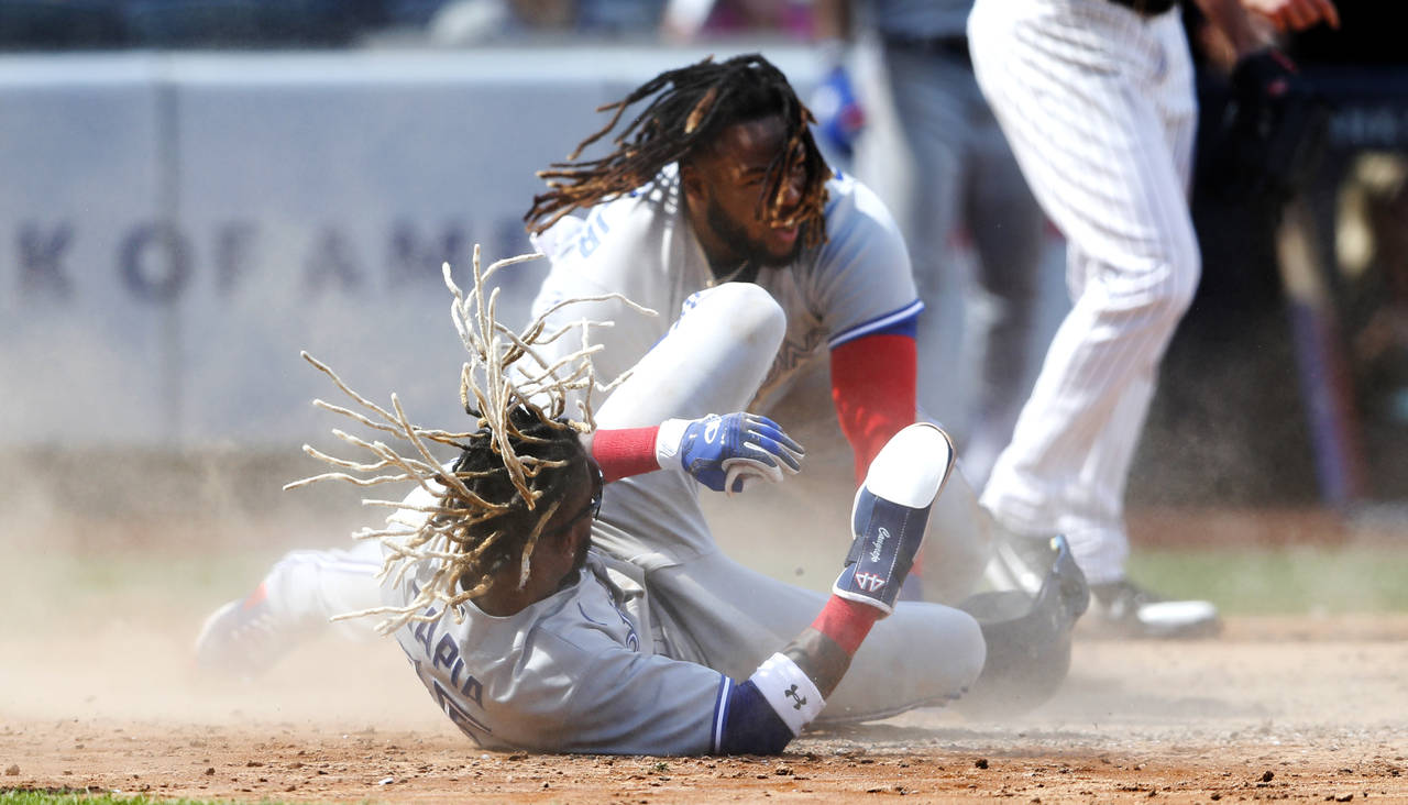 Toronto Blue Jays Vladimir Guerrero Jr., top, collides with teammate Raimel Tapia (15) after being ...