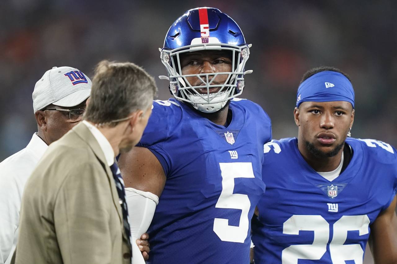 New York Giants' Saquon Barkley (26) checks on Kayvon Thibodeaux (5) as he is helped off the field ...