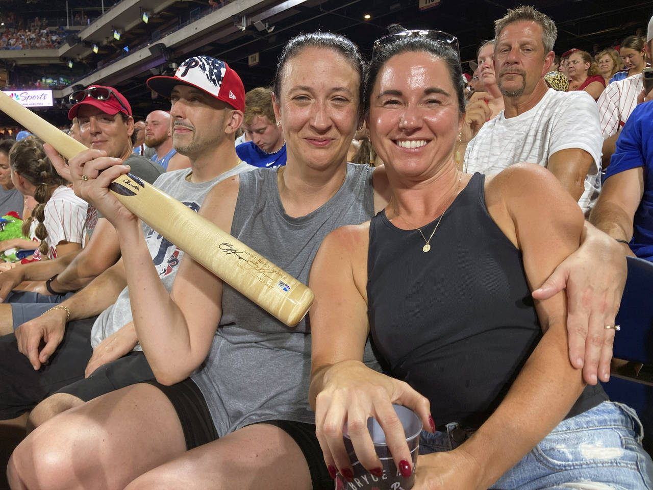 Kathie Koller, left, and Jen Mehall pose for a photo with a bat during a baseball game between the ...