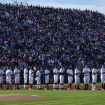 
              Cincinnati Reds players stand with fans for the national anthem before a baseball game against the Chicago Cubs at the Field of Dreams movie site, Thursday, Aug. 11, 2022, in Dyersville, Iowa. (AP Photo/Charlie Neibergall)
            