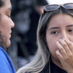 
              Tiffany Morales, 21, from Montebello, reacts as she visits a memorial for Los Angeles Dodgers broadcaster Vin Scully at the entrance to Dodger Stadium on Wednesday, Aug. 3, 2022, in Los Angeles. The Hall of Fame broadcaster, whose dulcet tones provided the soundtrack of summer while entertaining and informing Dodgers fans in Brooklyn and Los Angeles for 67 years, died Tuesday night. He was 94. (Dean Musgrove/The Orange County Register via AP)
            