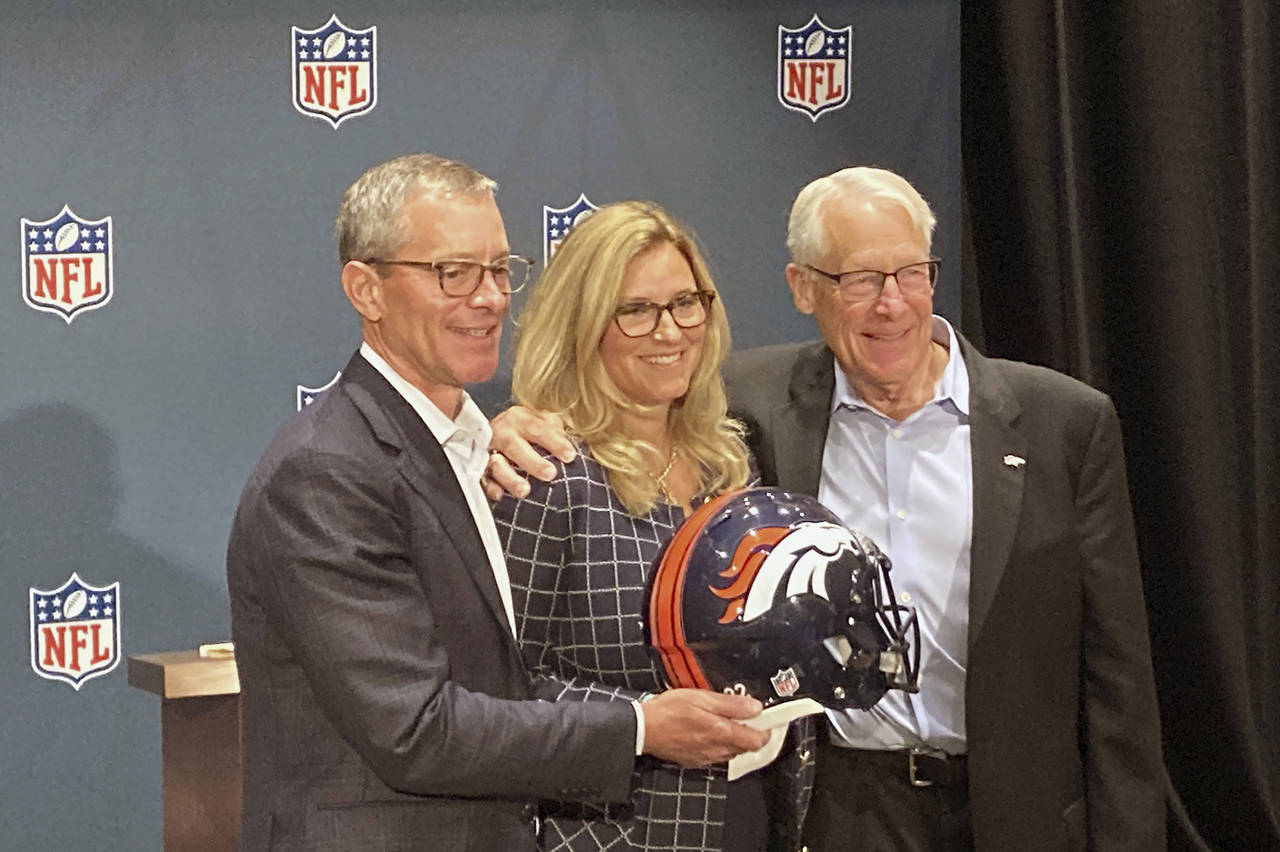 Greg Penner, left, Carrie Walton Penner, and Rob Walton pose at the NFL owners meeting in Bloomingt...