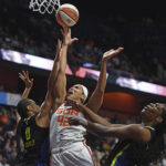 
              Dallas Wings forward Satou Sabally (0) fouls Connecticut Sun center Brionna Jones (42) as Wings center Teaira McCowan, right, helps on defense during Game 2 of a WNBA basketball first-round playoff series Sunday, Aug. 21, 2022, in Uncasville, Conn. (Sean D. Elliot/The Day via AP)
            
