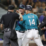 
              Seattle Mariners manager Scott Servais is held back by third base coach Manny Acta as he argues with plate umpire Dan Merzel after he was tossed out for arguing a strike out call on Mariners' Jesse Winker against the Cleveland Guardians during the eighth inning of a baseball game, Friday, Aug. 26, 2022, in Seattle. (AP Photo/John Froschauer)
            