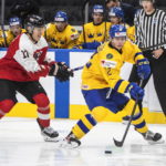 
              Sweden's Ludvig Jansson (12) and Austria's Senna Peeters (17) battle for the puck during third-period IIHF World Junior Hockey Championship action in Edmonton, Alberta, Friday, Aug. 12, 2022. (Jason Franson/The Canadian Press via AP)
            