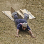 
              Boston Red Sox manager Alex Cora slides of a piece of cardboard half way down the hill in the outfield of Lamade Stadium during a visit to the Little League World Series in South Williamsport, Pa., Sunday, Aug. 21, 2022. The Red Sox will play the Baltimore Orioles in the Little League Classic on Sunday Night Baseball. (AP Photo/Gene J. Puskar)
            