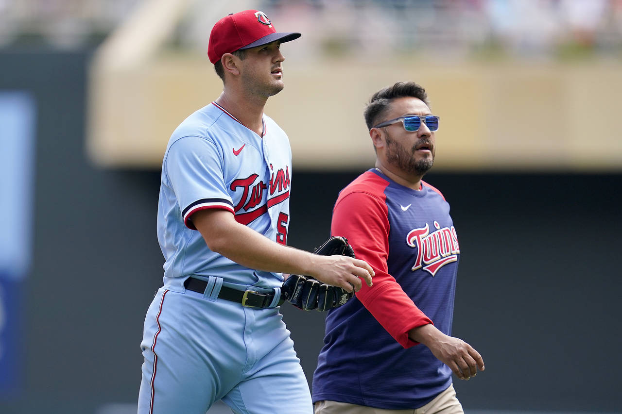 Minnesota Twins starting pitcher Tyler Mahle, left, exits the game with head athletic trainer Micha...