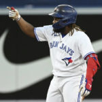 
              Toronto Blue Jays' Vladimir Guerrero Jr. gestures to the dugout after hitting a double against the Cleveland Guardians during the fourth inning of a baseball game Friday, Aug. 12, 2022, in Toronto. (Jon Blacker/The Canadian Press via AP)
            