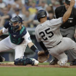 
              New York Yankees' Gleyber Torres (25) scores on a hit by Andrew Benintendi ahead of the throw with Seattle Mariners catcher Cal Raleigh, left, who waits for the ball during the third inning of a baseball game, Monday, Aug. 8, 2022, in Seattle. (AP Photo/John Froschauer)
            