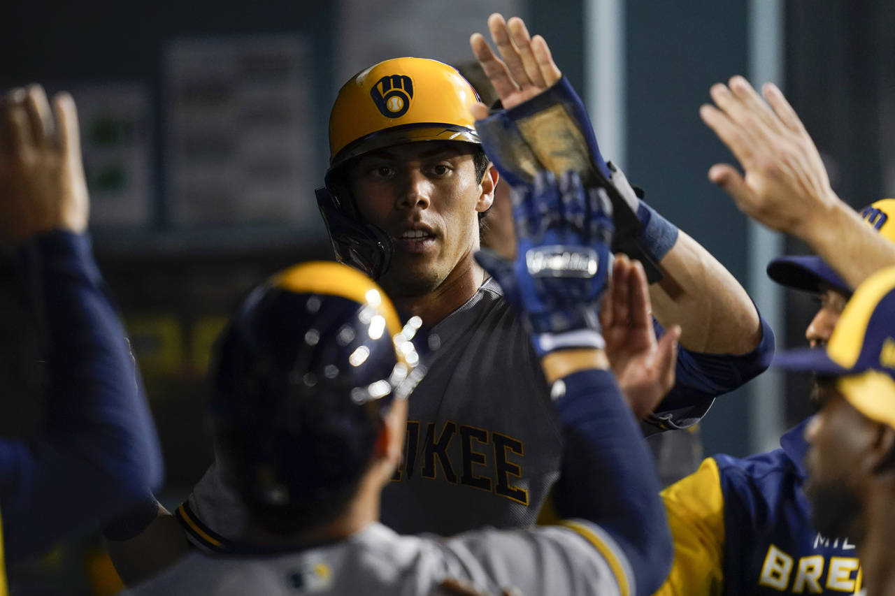 Milwaukee Brewers' Christian Yelich (22) celebrates in the dugout after scoring off of a sacrifice ...