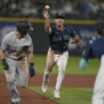 
              Seattle Mariners second baseman Adam Frazier, center, tosses the ball to shortstop J.P. Crawford, right, who caught New York Yankees' Andrew Benintendi, front left, in a rundown as Benintendi attempted to steal third base during the 10th inning of a baseball game Tuesday, Aug. 9, 2022, in Seattle. (AP Photo/Ted S. Warren)
            