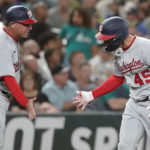 
              Washington Nationals' Joey Meneses (45) greets third-base coach Gary Disarcina, left, after he hit a solo home run against the Seattle Mariners during the seventh inning of a baseball game, Tuesday, Aug. 23, 2022 in Seattle. (AP Photo/Ted S. Warren)
            